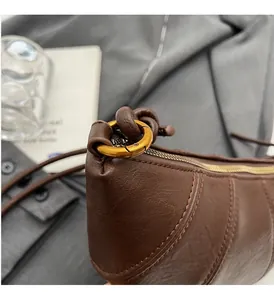 Gros plan d'un sac en cuir marron texturé avec boucle ronde en métal doré vintage