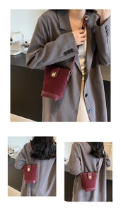 Detail of burgundy bucket bag featuring suede leather mix and gold metallic buckle