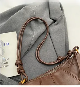 Détail d'un sac en cuir marron matelassé avec bandoulière nouée et boucle dorée rétro