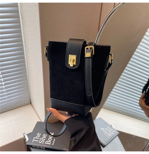 Detail of black matte suede bucket bag with gold lock and sleek leather stitching