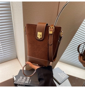 Detail of dark brown bucket bag featuring matte suede and smooth leather with gold clasp
