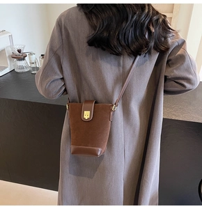 Detail of dark brown vintage bucket bag in suede with leather trim and gold twist lock