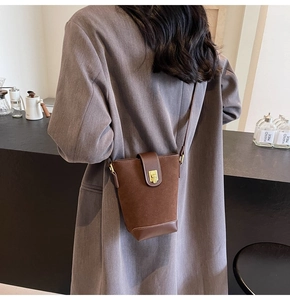 Detail of vintage brown suede bucket bag with gold metallic buckle and leather strap