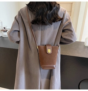 Detail of dark brown vintage bucket bag with suede leather and gold square buckle