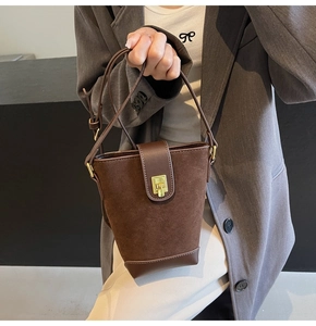 Detail of brown suede bucket bag featuring contrast leather trim and golden metal lock