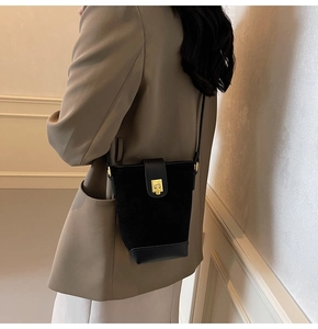Detail of vintage black bucket bag with suede texture and elegant gold square lock