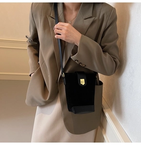 Detail of vintage suede bucket bag with gold clasp shown on a shoulder strap