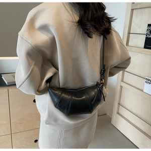 Détail d'un sac bandoulière noir en cuir en forme de croissant avec coutures plissées