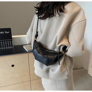Vue détaillée de la bandoulière nouée et de l'anneau en métal sur un sac noir en croissant