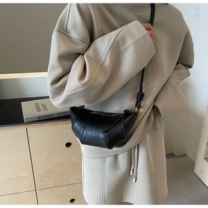Détail du sac croissant noir avec bandoulière nouée au style minimaliste français