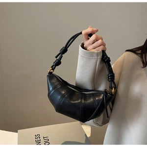 Détail du sac croissant noir avec poignée nouée et anneau métallique doré