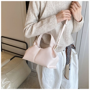 Detailed close-up of light pink lychee grain leather handbag with pleated design and gold metal