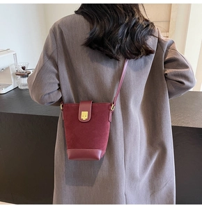 Detail of burgundy bucket bag with suede texture and gold square metal lock
