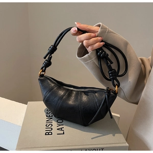 Détail du sac croissant noir avec bandoulière à nœud et garnitures métalliques rondes