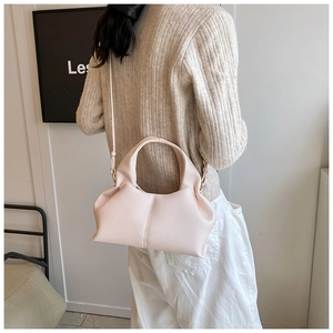Pink cloud shoulder bag with pleated texture worn over a beige knit top for a chic look