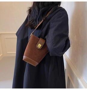 Close-up of vintage brown suede bucket bag with gold metal clasp on blue coat