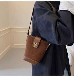 Detail of caramel brown suede bucket bag featuring a gold square lock and leather strap