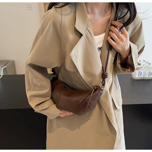 Détail du sac croissant en cuir marron foncé avec texture plissée et bandoulière nouée