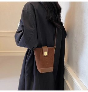 Detail of dark brown suede and leather bucket bag with retro gold clasp closure