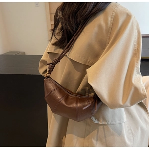 Détail d'un sac croissant marron foncé montrant le cuir souple et la bandoulière nouée