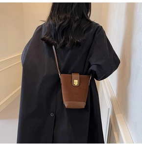 Detail view of a vintage brown frosted leather bucket bag with a gold metal lock