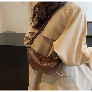 Détail d'un sac demi-lune marron vintage avec cuir plissé et bandoulière à nœud décoratif