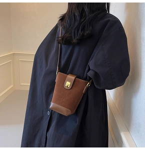 Detail of vintage brown suede bucket bag with gold metallic buckle and leather texture