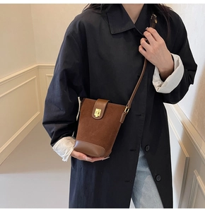 Detail of dark brown vintage bucket bag with suede texture and golden metal buckle clasp