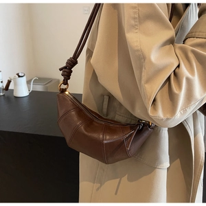 Détail du sac croissant marron foncé avec cuir matelassé et bandoulière à nœuds
