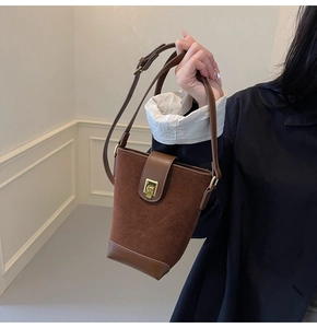 Detail of brown suede bucket bag with gold metal lock and adjustable leather strap