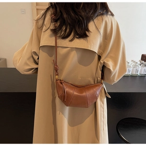 Détail d'un sac croissant en cuir marron avec design plissé et bandoulière nouée