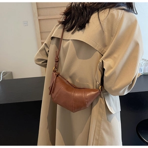 Détail du sac croissant marron montrant la texture plissée du cuir et anneaux métal