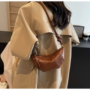 Détail du sac croissant marron avec texture plissée et bandoulière nouée de style élégant