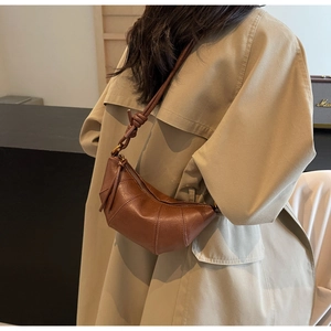 Sac croissant en cuir marron avec détail de nœud porté sur un trench-coat beige