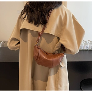 Sac croissant en cuir marron porté épaule avec bandoulière nouée et texture vintage chic
