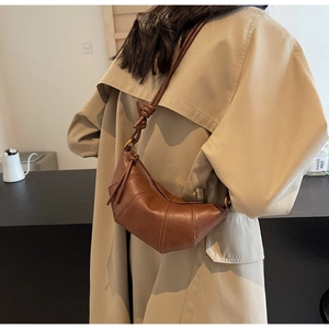 Sac croissant marron vintage à plis porté avec un trench-coat élégant et moderne