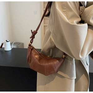 Sac croissant matelassé marron porté sur un trench-coat montrant texture et style