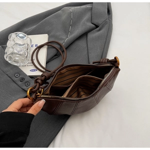 Détail macro du sac en cuir marron foncé montrant les compartiments et la doublure