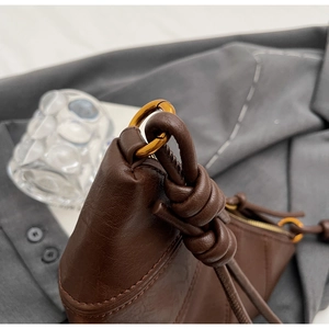 Gros plan détaillé de la bandoulière nouée en cuir marron et de l'anneau doré du sac