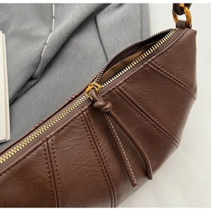 Gros plan détaillé du sac croissant en cuir marron foncé avec design plissé et zip métallique