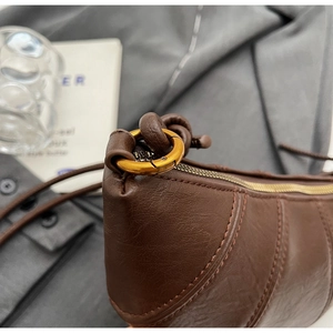 Détail du cuir grainé marron foncé avec boucle en métal bronze et fermeture éclair