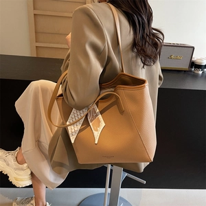 Brown litchi leather tote bag with geometric print scarf handle shown on shoulder