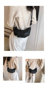 Detail of black crescent crossbody bag with pleated texture and knotted strap detail