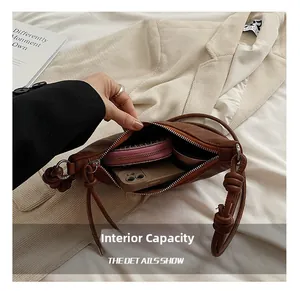 Detail showing internal capacity of brown leather crossbody bag with items and knotted strap