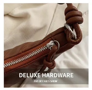 Close-up of silver metal zipper and knotted leather strap on brown crossbody bag