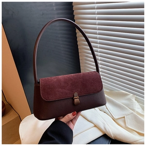 Detail of burgundy baguette bag featuring suede flap and elegant gold clasp closure