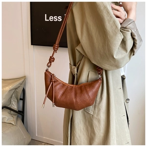 Detail of a dark brown croissant bag with pleated PU leather and a knotted shoulder strap