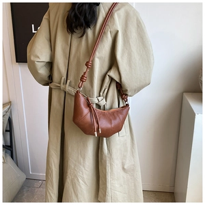 Detail of a brown leather croissant bag with pleated design and knotted shoulder strap