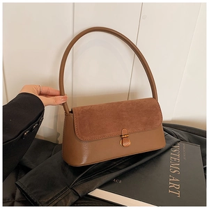 Détail du sac baguette marron avec patchwork en daim et fermoir rotatif doré élégant