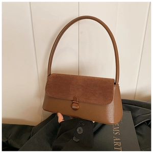 Detailed shot of brown vintage baguette bag with suede flap and metal lock